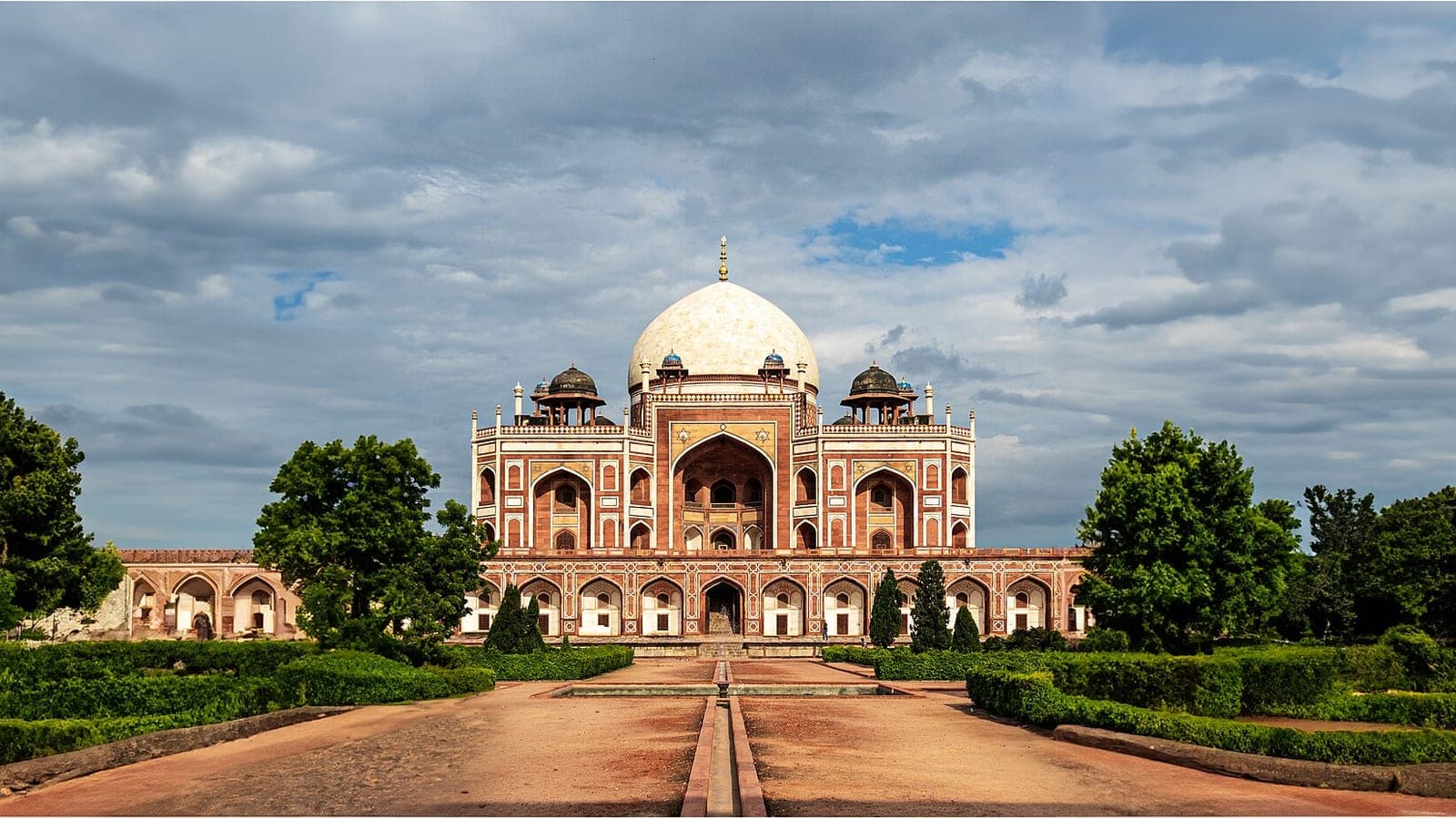 Humayun's Tomb seen straight down the central axis of its char-bagh garden, the white dome centred above the arched façade.