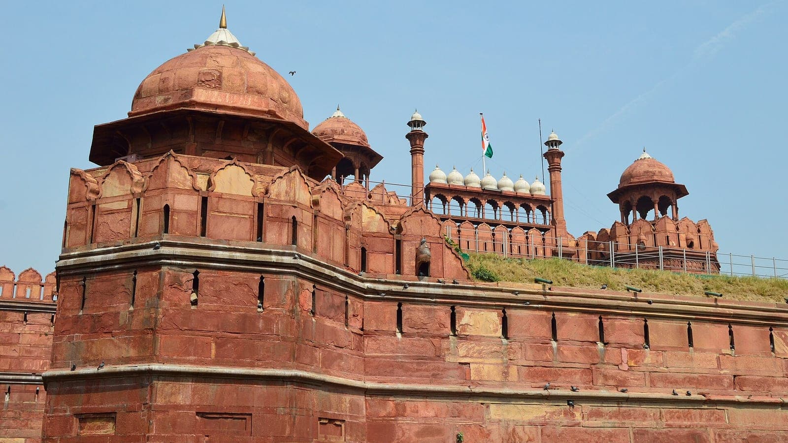 The red sandstone ramparts of the Red Fort at Lahori Gate, the Indian tricolour flying above the gatehouse.
